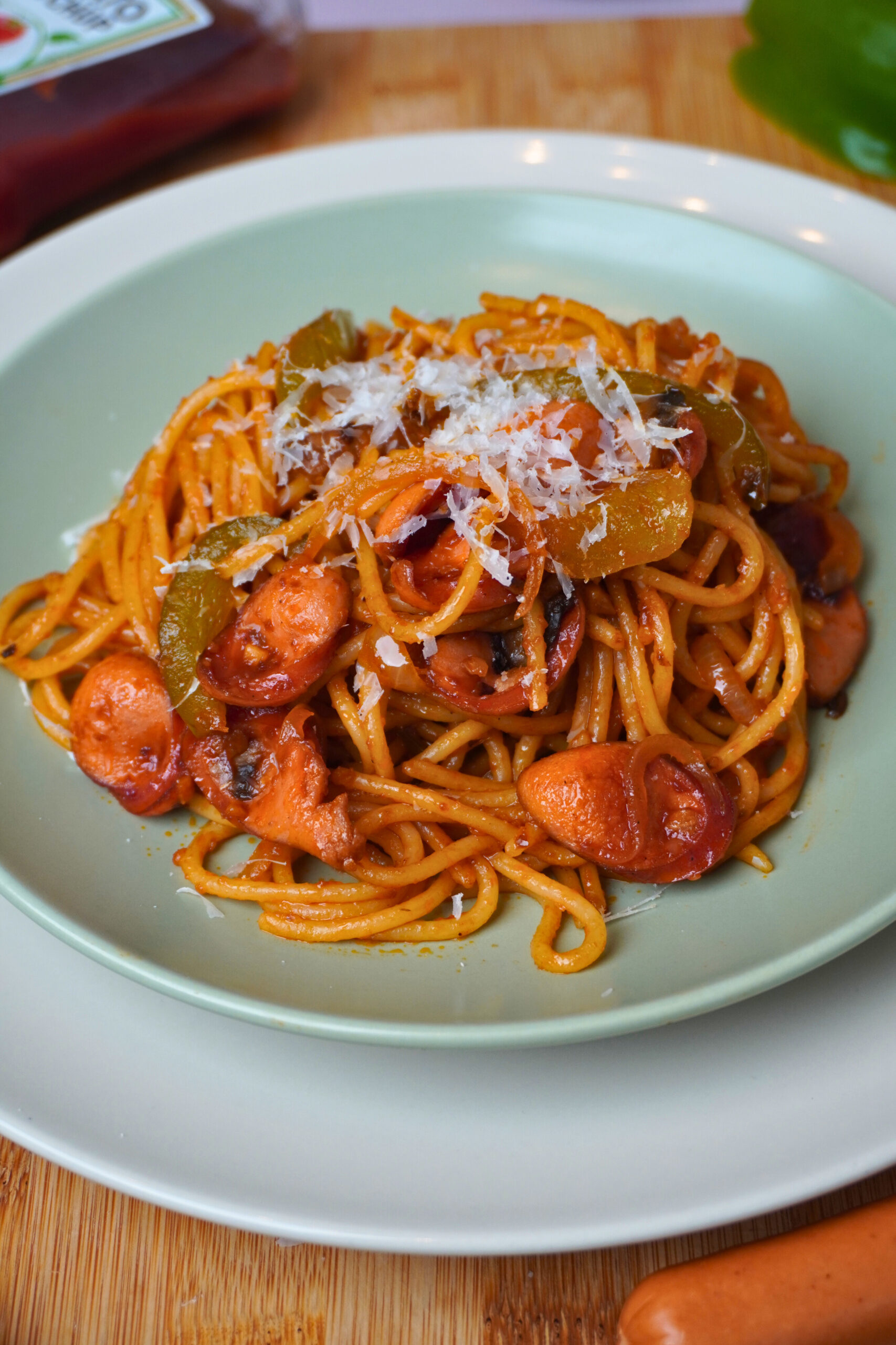 Japanische Ketchup Spaghetti auf grünem Teller mit Parmesankäse